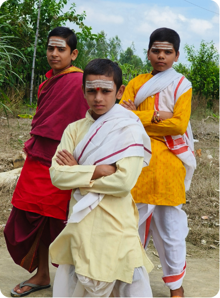 Three students in traditional attire standing confidently outdoors