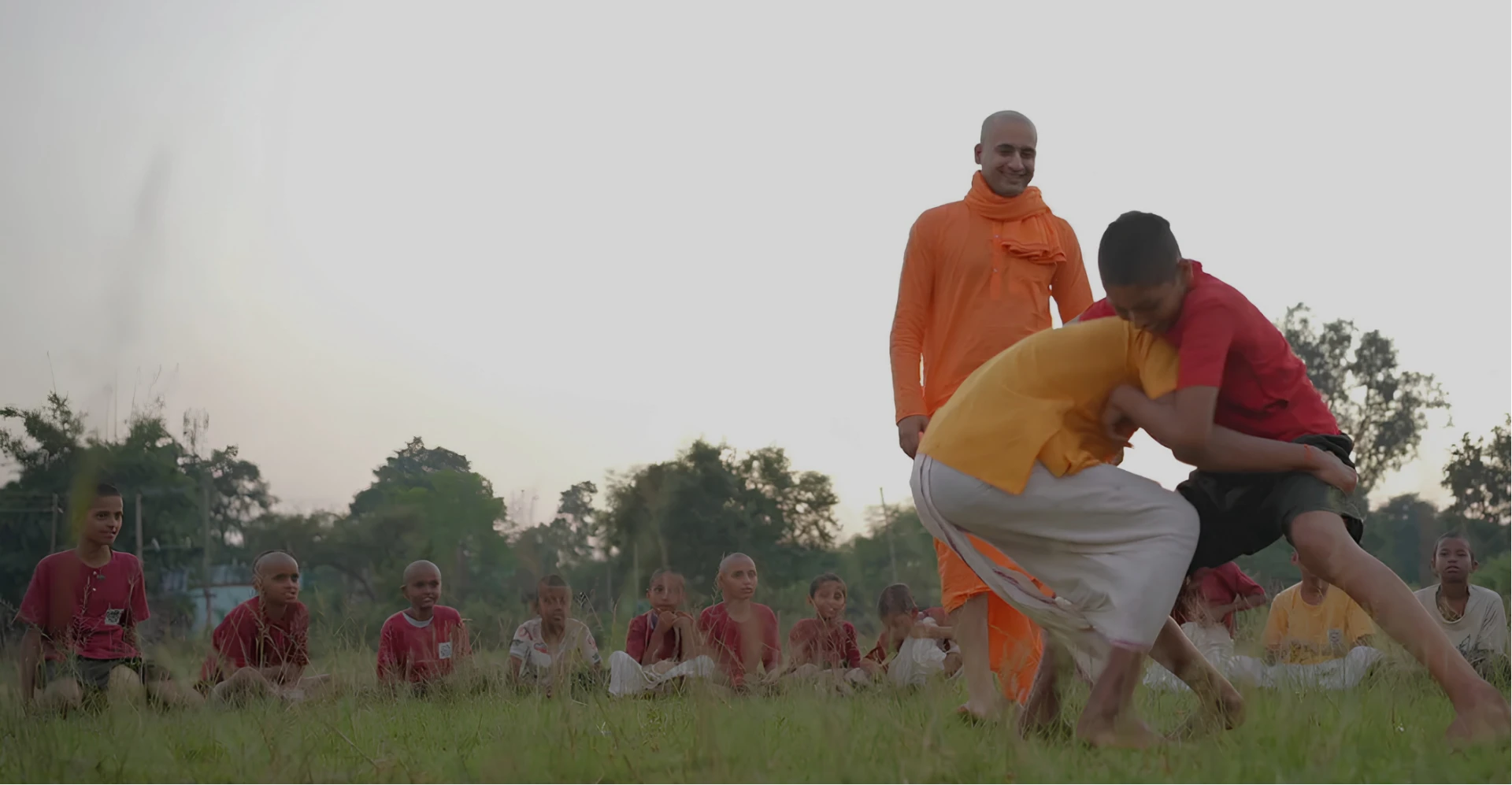 Gurukul students practising wrestling in a field with their acharya